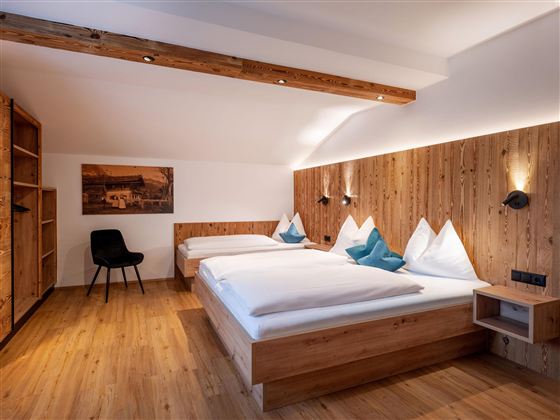 Een moderne kamer met houten details en gezellige bedden. De ontspannen sfeer nodigt uit om te blijven hangen.