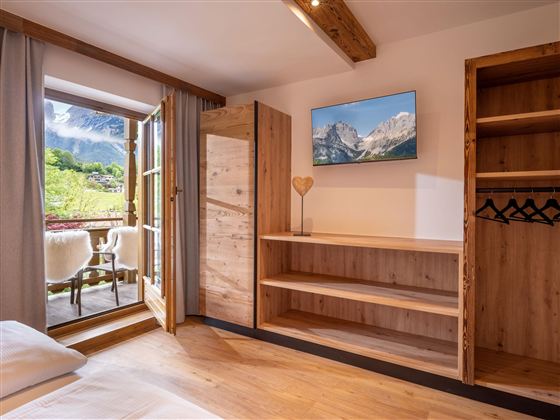 Een moderne kamer met houten planken en een tv. Door de open deuren ziet men een prachtig uitzicht op de bergen.