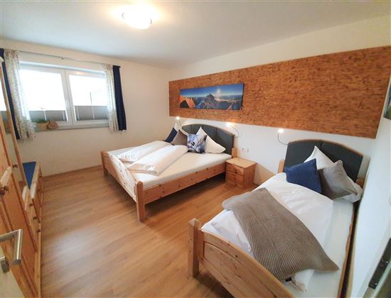 Ein gemütliches Schlafzimmer mit zwei Einzelbetten und Holzverkleidung. Das Zimmer ist hell und freundlich mit großen Fenstern.