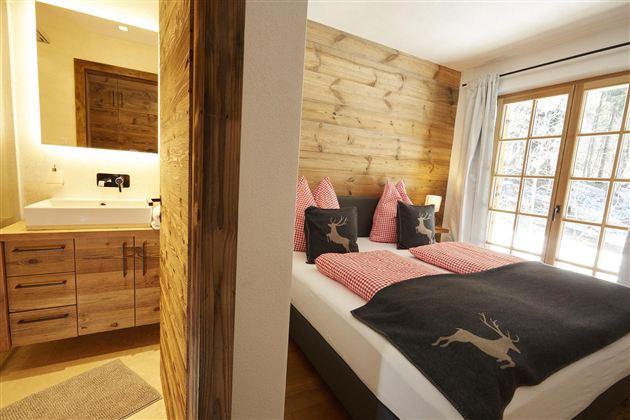 Ein gemütliches Schlafzimmer mit Holzverkleidung und einem modernen Badezimmer. Die Fenster bieten viel Licht und einen schönen Ausblick.
