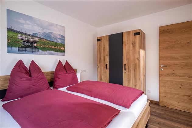 Een moderne slaapkamer met een tweepersoonsbed en een afbeelding van een berglandschap.