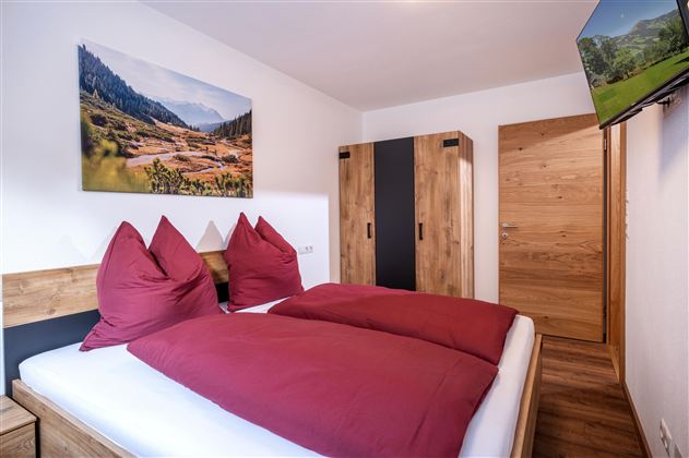 Een gezellige slaapkamer met een tweepersoonsbed en een landschapsschilderij aan de muur.