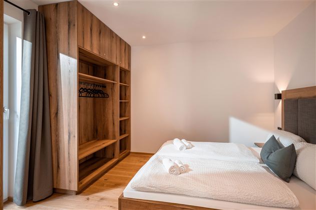 Ein modernes Schlafzimmer mit zwei Einzelbetten und Holzmöbeln. Der Raum ist hell und freundlich mit viel Stauraum.