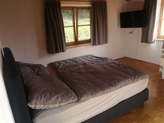 Schlafzimmer mit Doppelbett, Schrank und Fernseher