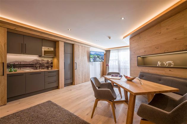 Modern apartment with open kitchen and wooden furniture. Bright atmosphere with large windows and a stylish color concept.