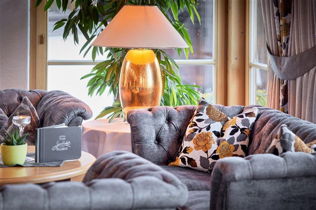 A stylishly furnished living area with a gray sofa and decorative cushions. A beautiful lamp and a plant create an inviting atmosphere.