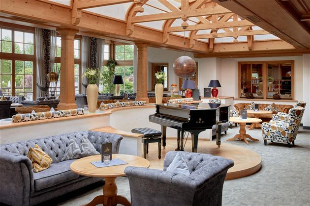 Een elegante woonkamer met een piano in het midden. Gezellige banken en stoelen creëren een uitnodigende sfeer.