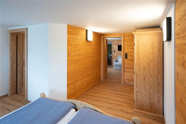 A cozy room with wooden walls and modern design. The room features a double bed and a large wardrobe.