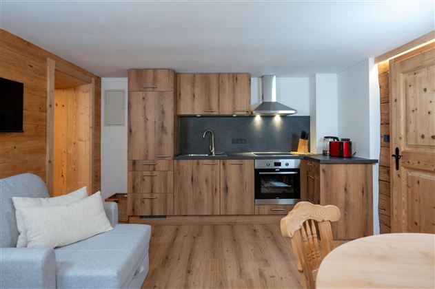 A modern kitchen with wooden cabinets and stainless steel appliances. The room is bright and offers a cozy atmosphere.