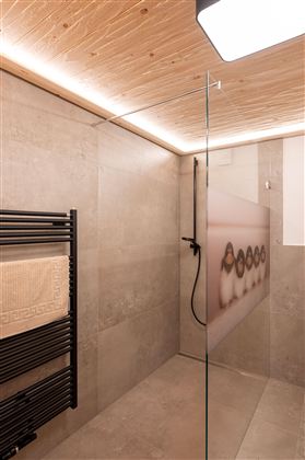A modern bathroom with a glass shower cabin and a stylish wall covering. The room is decorated in neutral tones and features soft lighting.