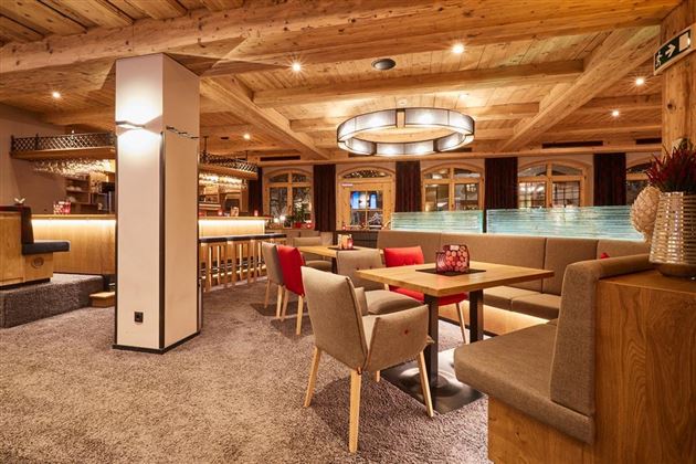 Eine gemütliche Inneneinrichtung mit Holzdetails und warmem Licht. Moderne Möbel und eine einladende Bar schaffen eine entspannte Atmosphäre.