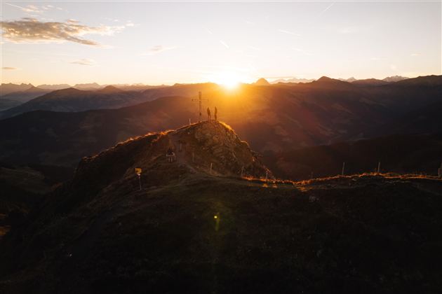 A breathtaking sunset over the mountains. The silhouettes of people stand on a peak, enjoying the view.