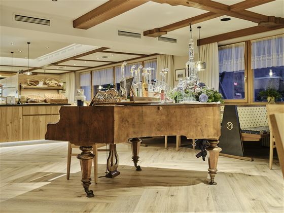 Ein elegantes Klavier steht in einem gemütlichen Raum mit Holzdekor. Die Atmosphäre ist warm und einladend, ideal für entspannende Momente.