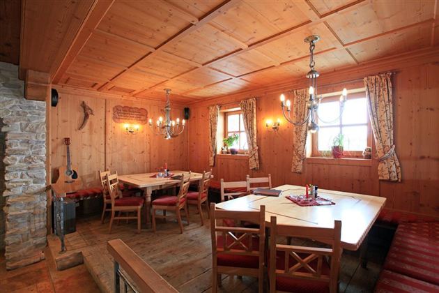 Unsere gemütliche Stube mit Holzdecken und warmem Licht. Es gibt auch genügend Platz für Gruppen.