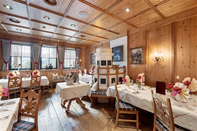 Ein gemütliches Restaurant mit Holzdekor und festlich gedeckten Tischen. Im Raum sind traditionelle Elemente und eine warme Atmosphäre zu sehen.