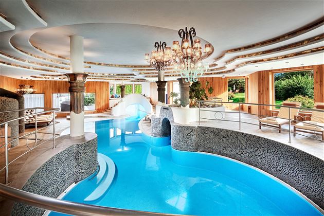 An elegant spa with a blue pool and stylish interior. Large windows offer a beautiful view of the outdoors.