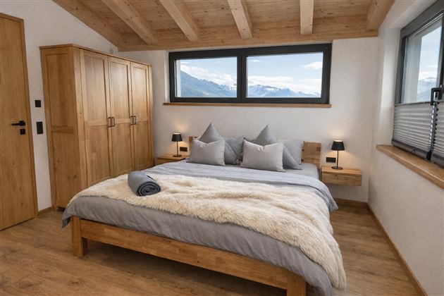 Ein modernes Schlafzimmer mit einem großen Bett und Holzdekor. Große Fenster bieten einen Blick auf die Berge.