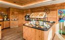 Een uitnodigende ontbijtruimte met houten panelen en een buffet vol verse gerechten. Op de tafel liggen verschillende broden, vleeswaren en fruit.