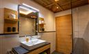 A modern bathroom with wooden shelves and a sink on a stylish base cabinet. The lighting is soft and creates a pleasant atmosphere.