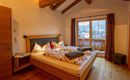 A cozy bedroom with wood paneling and a large double bed. Large windows offer a beautiful view of nature.
