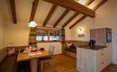 A cozy kitchenette with a dining table and seating area. Bright wooden beams give the room a warm atmosphere.