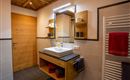 A modern bathroom with wooden details and an elegant sink cabinet. The room is bright and well-lit, with towels in various colors.