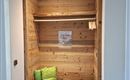 A cozy entrance area with wooden shelves and a bench. Two green cushions provide additional comfort.