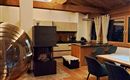 A modern living room with a wooden ceiling and elegant furniture. The room is brightly lit and conveys a cozy atmosphere.