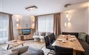 A modern living room with a large dining table and comfortable seating. 

Large windows let in plenty of light and create a cozy atmosphere.