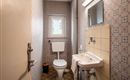 A small bathroom with a toilet and a sink. The walls are decorated with patterned wallpaper.