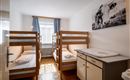 A simple bedroom with two bunk beds and a wardrobe. On the wall hangs a picture of cows.