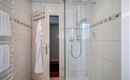 A modern bathroom with a glass shower. White tiles and a towel rack complete the furnishings.