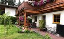 Een gezellig huis met een mooi balkon, dat versierd is met kleurrijke bloemen. De tuin biedt een uitnodigende zitplek en een groen gazon.
