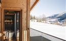 Eine moderne Holzterrasse mit Blick auf schneebedeckte Berge. Die Einrichtung ist gemütlich und einladend.