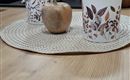 A beautiful set table with a round placemat. On the table are two decorative cups and a small wooden apple.