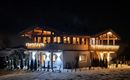 Ein hell erleuchtetes Haus in einer verschneiten Umgebung bei Nacht. Die festliche Beleuchtung schafft eine gemütliche Atmosphäre.