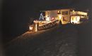 A beautifully lit house in the snow. Christmas lights and a decorated tree create a festive atmosphere.
