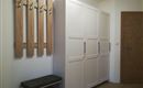 A modern hallway with a white closet and a bench. Wooden coat hooks are hanging on the wall.