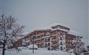A large building in a snowy landscape. The winter snow covers roofs and trees.