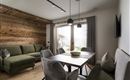 A stylish living room with a green couch and a modern dining table.  
Large windows let in plenty of light and provide a view outside.