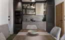 A modern kitchen with dark cabinets and white accents. A dining area with a wooden tray and comfortable chairs is also visible.