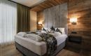 A cozy bedroom with a large bed, modern design, and wooden walls.  
Large windows let in plenty of light and create an inviting atmosphere.