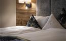 A cozy bedroom with a modern bed and decorative cushions. Soft light creates an inviting atmosphere.