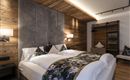 A modern bedroom with a large double bed and cozy wood paneling. The decorative pillows and soft lighting create an inviting atmosphere.
