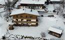 A cozy wooden house in a snowy landscape. Surrounded by snow-covered trees and a peaceful winter environment.