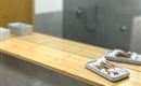 Een modern badkamer met een houten plank en een wastafel. Op de achtergrond is een inloopdouche te zien.
