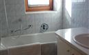 A bright bathroom with a bathtub, a sink, and a window. The tiles are in light colors and create a friendly atmosphere.