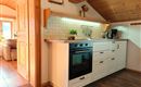 Een moderne keuken met een witte keukenlijn en een zwarte fornuis. De houtdecoratie en de warme verlichting geven de keuken een gezellige sfeer.