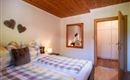 Ein gemütliches Schlafzimmer mit zwei Betten und bunten Decken. Im Hintergrund sind ein Spiegel und ein Kleiderschrank zu sehen.