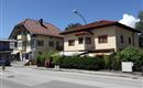 Two traditional buildings on a street in a quiet surroundings. The sky is blue with few clouds.